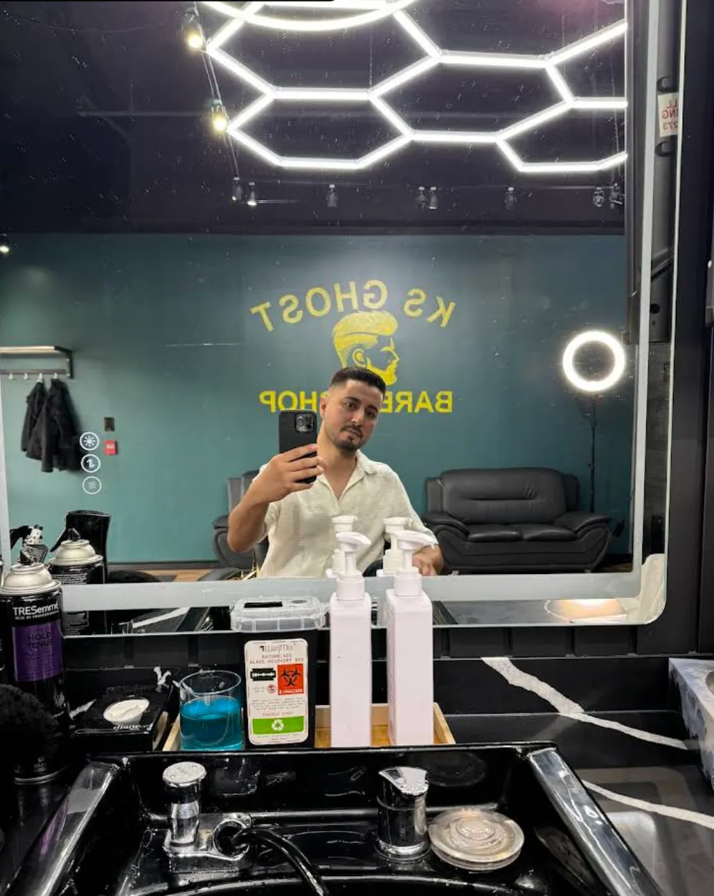 Mirror selfie revealing the KS Ghost Barbershop logo in teal and gold lettering